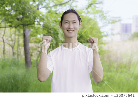 Portrait of a young man posing with both hands in a park 126075641