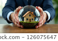 person holding glass globe showcasing a miniature house, representing sustainable living and real estate investment, real estate insurance 126075647