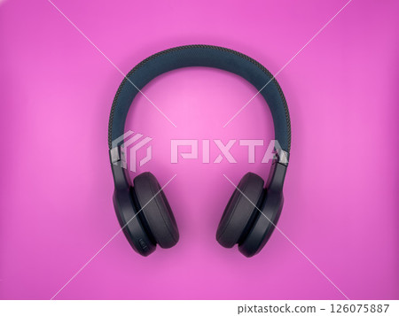 Full-size large headphones made of green plastic with soft earphones and a soft headband lie in the center of the image on a pink background one item 126075887