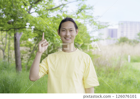 Portrait of a young man doing the number 1 pose in a park 126076101