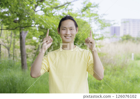 Portrait of a young man doing the number one pose with both hands standing in the park Portrait of a young man doing the number one pose with both hands standing in the park 126076102