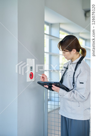 A woman inspecting emergency alarm equipment A woman inspecting emergency alarm equipment 126076120