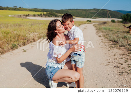 Mother with son walking in a rural field in summer by the road 126076339