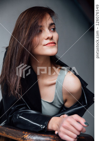 Portrait of a beautiful brunette woman in a leather jacket on a gray background 126076549