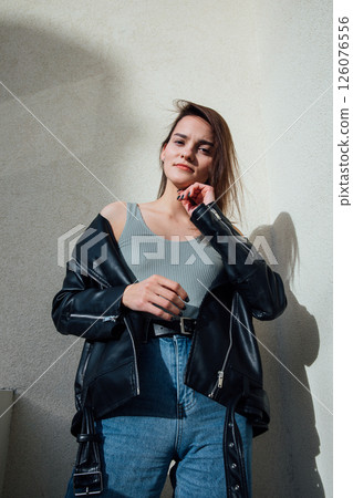 brunette woman posing in jeans and black leather jacket brunette woman posing in jeans and black leather jacket 126076556