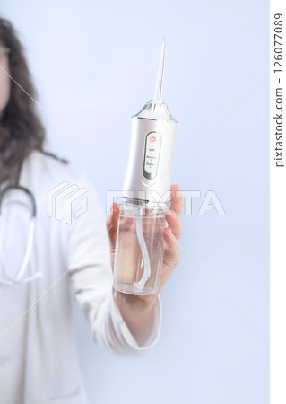 Female dentist explains how to use an oral irrigator which tips to choose and why daily water cleaning is essential for oral health. 126077089