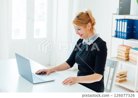 Woman sitting at desk with laptop and smiling 126077326