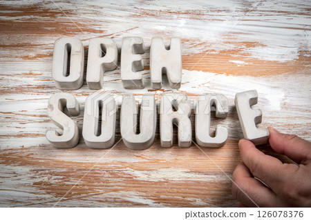 Open Source. Concrete alphabet letters on a light painted wood texture background Open Source. Concrete alphabet letters on a light painted wood texture background 126078376