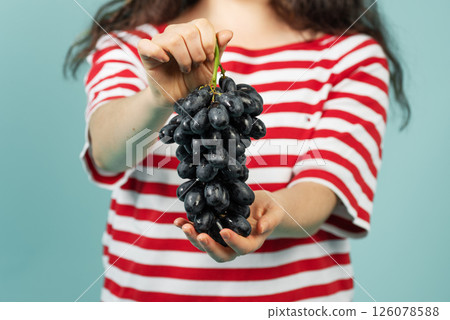 Close-up of young woman holding black grapes 126078588