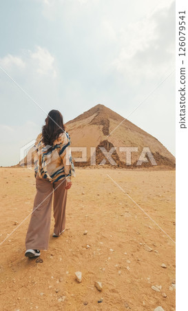 Tourist walking away from bent pyramid in the desert of egypt 126079541