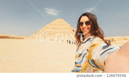 Tourist taking selfie with the step pyramid of djoser in saqqara, egypt Tourist taking selfie with the step pyramid of djoser in saqqara, egypt 126079548