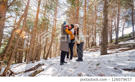 Friends taking selfie in snowy forest during winter hike Friends taking selfie in snowy forest during winter hike 126079657