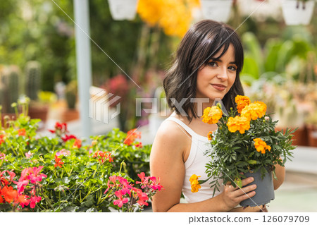 Gardener holding pot with marigold flowers in greenhouse Gardener holding pot with marigold flowers in greenhouse 126079709