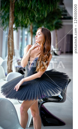 Elegant ballerina in black tutu posing gracefully with hand near face Elegant ballerina in black tutu posing gracefully with hand near face 126080000