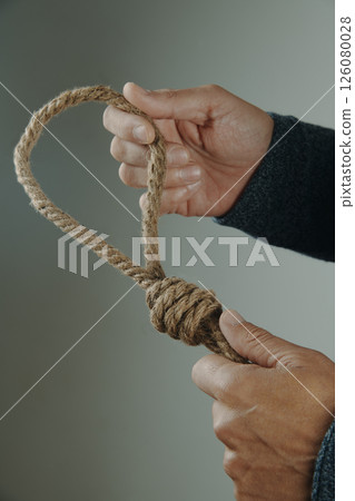 closeup of a man holding a jute rope with a noose 126080028