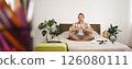 Portrait of young relaxed tourist, man sitting on bed with crossed legs and meditating, has packed luggage, globe and camera, going on holiday, calms down before going on a trip 126080111