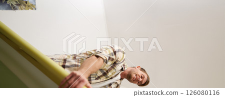 Vertical shot of man trying to press suitcase and close zipper, packing clothes for vacation. Tourist going on holiday, preparing for travelling abroad 126080116