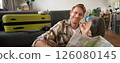 Smiling handsome tourist, man with road travel map, sits on floor near suitcase, shows okay, ok sign, recommending a tour 126080145