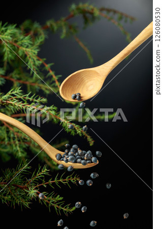 Juniper seeds are sprinkled with a wooden spoon. Juniper seeds are sprinkled with a wooden spoon. 126080530