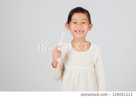 A kid with a missing tooth holds a toothbrush happily. The dentist discusses tooth loss, helping children learn a good dental care routine for healthy teeth. isolated white background 126081221