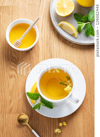 Cup of herbal tea with lemon, honey and mint on wooden tabletop with citrus fruits Cup of herbal tea with lemon, honey and mint on wooden tabletop with citrus fruits 126082448