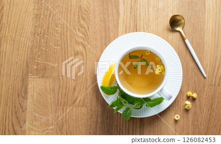 Cup of herbal tea with lemon, honey and mint on wooden tabletop with citrus fruits Cup of herbal tea with lemon, honey and mint on wooden tabletop with citrus fruits 126082453