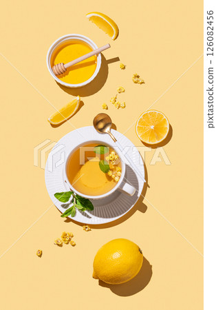 Cup of herbal tea with lemon, honey and mint on yellow background with citrus fruits and shadows. Cup of herbal tea with lemon, honey and mint on yellow background with citrus fruits and shadows. 126082456