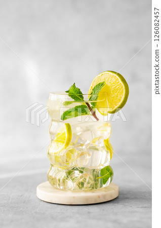 Mojito cocktail in a glass with lime, mint and ice on a textured background with natural light 126082457