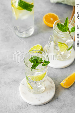 Two glasses mojito cocktail with fresh lime, mint and ice on a marble stand on light background Two glasses mojito cocktail with fresh lime, mint and ice on a marble stand on light background 126082471