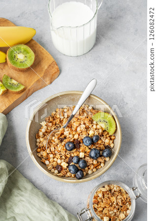 Homemade baked granola or muesli in a bowl with kiwi and blueberries on a light background Homemade baked granola or muesli in a bowl with kiwi and blueberries on a light background 126082472