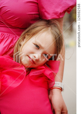 Cute girl in a pink dress in her mother's arms.  126082588