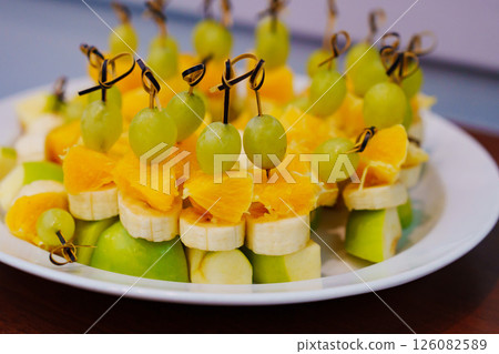 A plate with fruity canapes made from apples, bananas, oranges and grapes. A plate with fruity canapes made from apples, bananas, oranges and grapes. 126082589