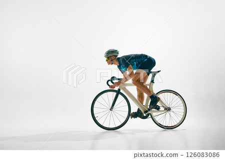 Side view image of young concentrated man, professional cyclist in motion on bicycle, riding isolated on white background. 126083086