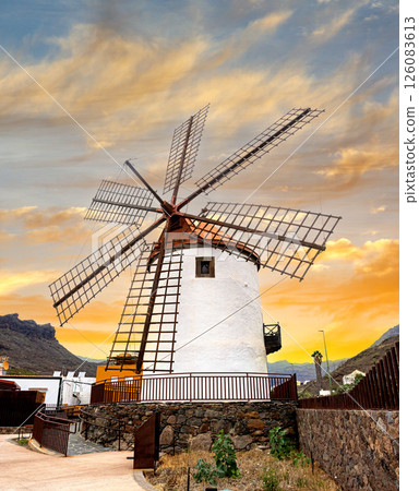 Traditional windmill standing tall against a vibrant sunset in mogan, gran canaria 126083613