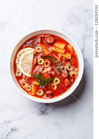 Traditional soup solyanka with smoked sausages, olives and potatoes. Traditional soup solyanka with smoked sausages, olives and potatoes. 126084182