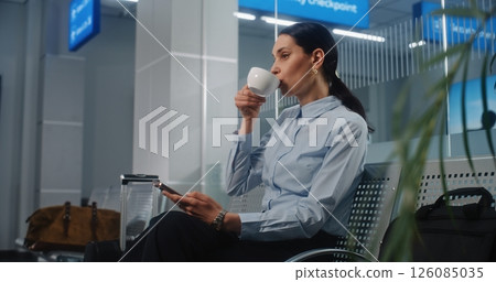 Airport Terminal: Female Entrepreneur Sitting in VIP Departure Lounge, Using Smartphone and Drinking Coffee Airport Terminal: Female Entrepreneur Sitting in VIP Departure Lounge, Using Smartphone and Drinking Coffee 126085035