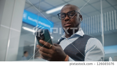 Airport Terminal: Man Scanning Airplane Ticket Using Smartphone, Checking Information Airport Terminal: Man Scanning Airplane Ticket Using Smartphone, Checking Information 126085076