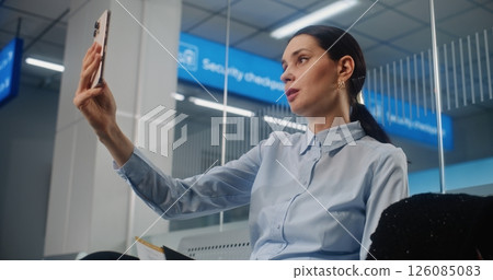 Businesswoman Talking to Business Partner on Smartphone by Video Call, Waiting for Airplane Flight 126085083