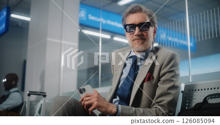 Airport Terminal: Mature Businessman Using Smartphone and Drinking Coffee, Looking at Camera 126085094