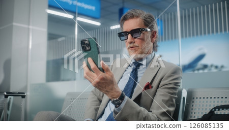 Airport Terminal: Entrepreneur Talking to Investor on Smartphone by Video Chat, Drinking Coffee 126085135
