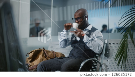 Airport Terminal: Businessman Sitting in Departure Lounge, Drinking Coffee Airport Terminal: Businessman Sitting in Departure Lounge, Drinking Coffee 126085172