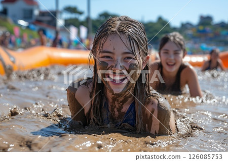 participants covered in mud during a playful fight at Boryeong Mud Festival, with inflatable mud pits in the background 126085753