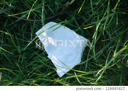 A piece of tissue is laying on the grass 126085827