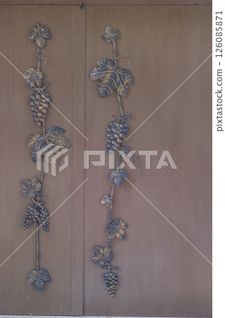 Decorative metal grapevines decorating wooden door Decorative metal grapevines decorating wooden door 126085871