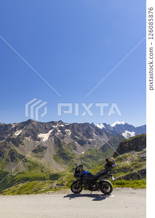 Motorcycle parked on a mountain road overlooking the French Alps Motorcycle parked on a mountain road overlooking the French Alps 126085876