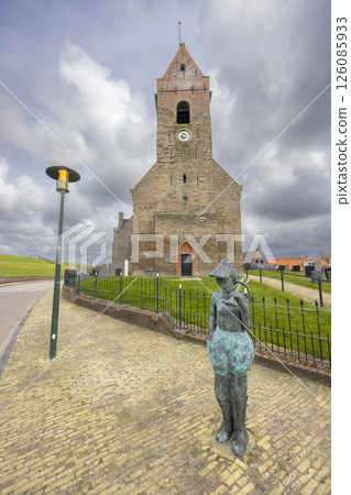 Statue of a boy holding a fish in front of Wierum church in Friesland, Netherlands 126085933