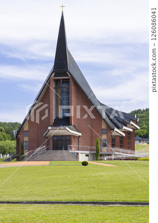 Church of Saint Roch in Jasienica Rosielna presenting its modern architecture under a cloudy sky Church of Saint Roch in Jasienica Rosielna presenting its modern architecture under a cloudy sky 126086041