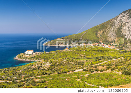 Sea coast of the Peljesac Peninsula in Croatia, Europe. Picturesque coastal village nestled among green hills with turquoise sea and clear sky in background on a sunny day. Idyllic seaside getaway. 126086305