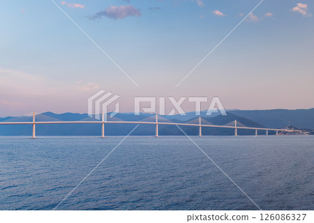 The Peljesac Bridge to Peljesac peninsula in Croatia, Europe. Scenic bridge stretches across the calm water, connecting distant shores under a serene sky during the tranquil hours of the day. 126086327