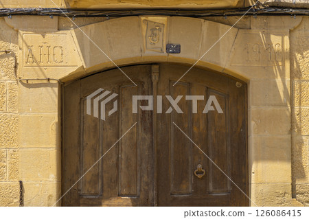 Old wooden door of a house built in 1916 in Uncastillo, Spain, showing signs of aging Old wooden door of a house built in 1916 in Uncastillo, Spain, showing signs of aging 126086415